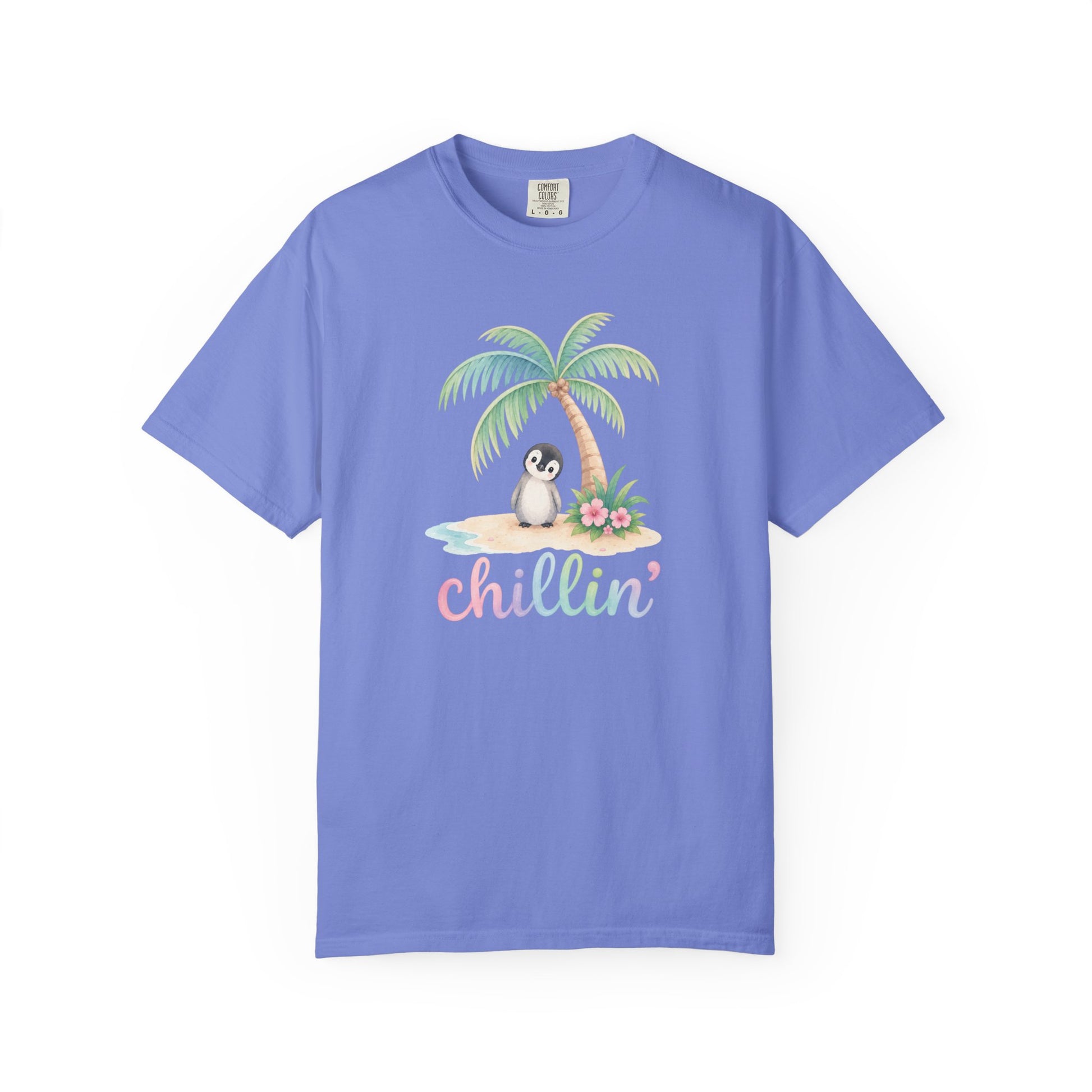 A light blue/purple short-sleeve crewneck t-shirt featuring a colorful graphic of a penguin sitting under a palm tree on a beach with the word 'chillin'' written below in pastel letters, displayed on a clean white background.