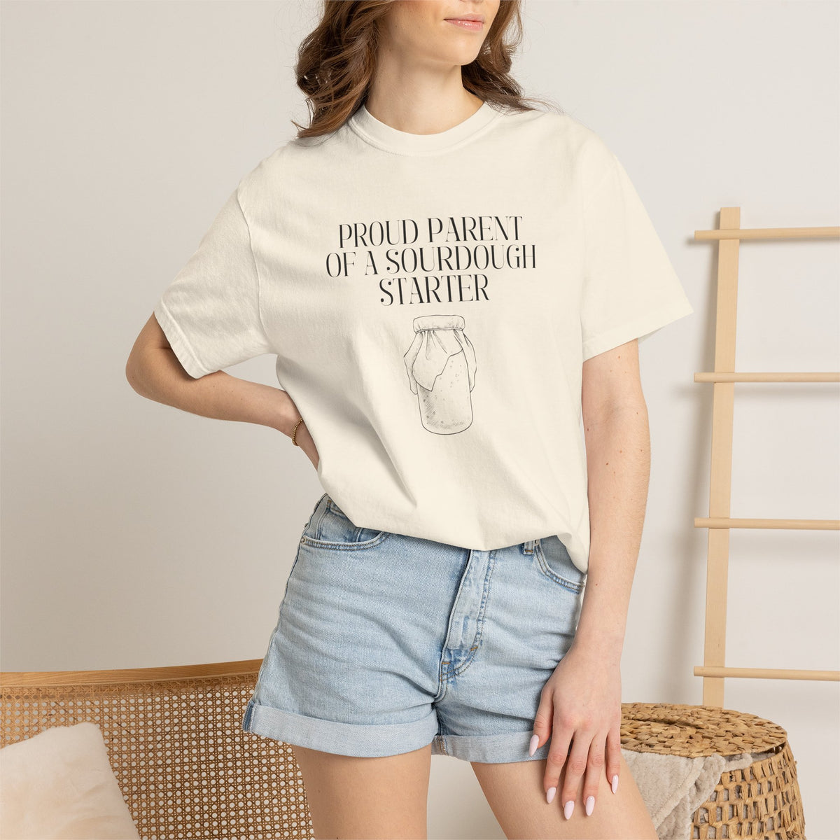 Model wearing an off white Comfort Colors® "Proud Parent of a Sourdough Starter" t-shirt with vintage sourdough jar illustration graphic. Funny sourdough shirt for bakers, bread makers, and homemade bread enthusiasts.