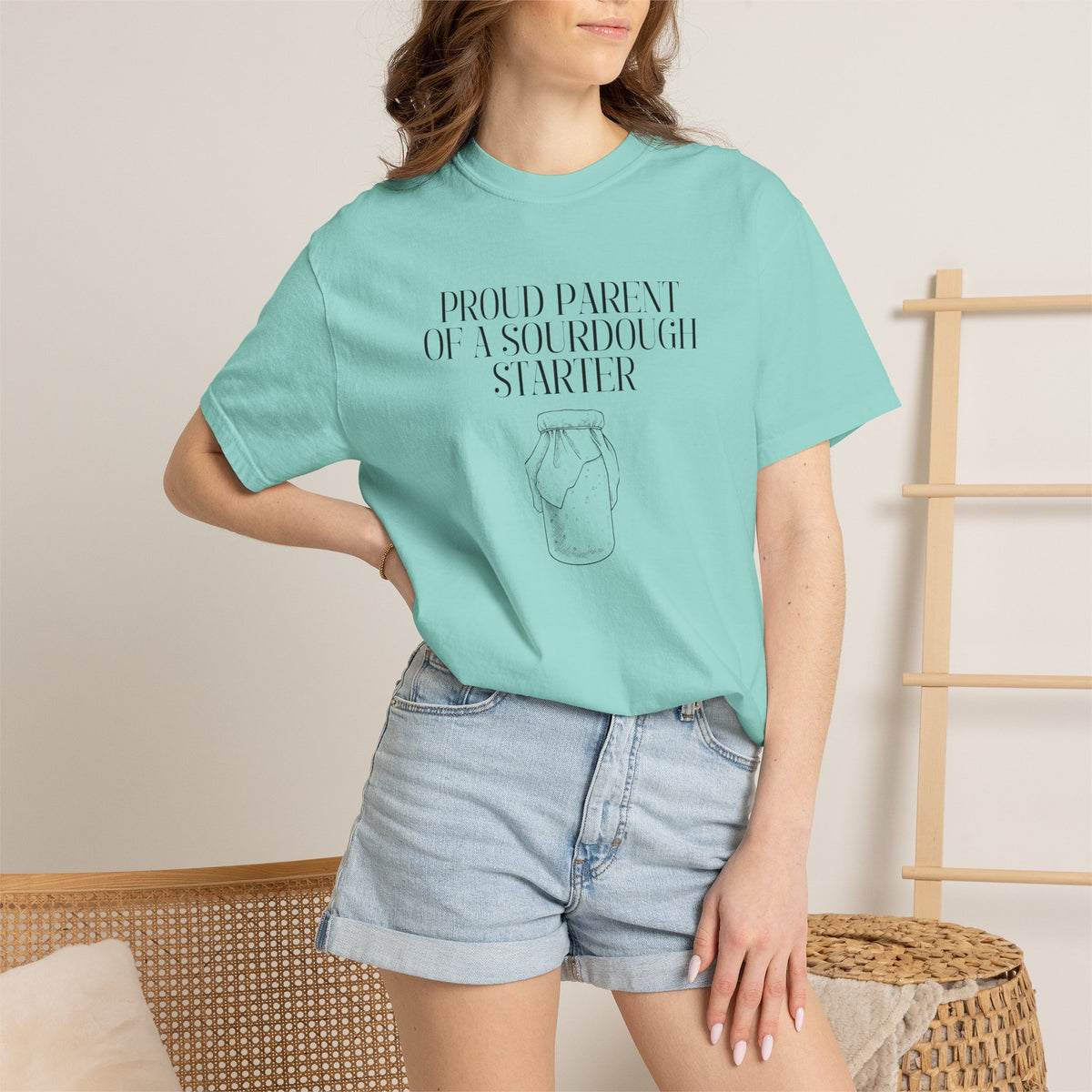 Model standing and wearing a mint green Comfort Colors® "Proud Parent of a Sourdough Starter" t-shirt with vintage sourdough jar graphic. Funny sourdough shirt for bakers, bread makers, and homemade bread enthusiasts.