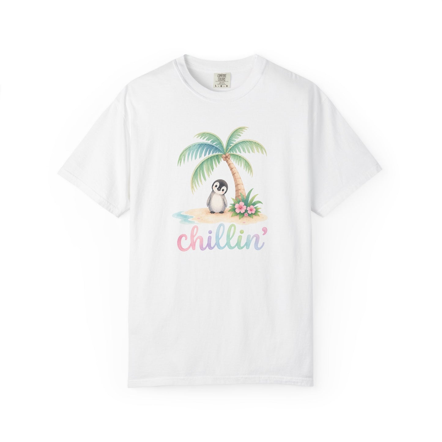 A white short-sleeve crewneck t-shirt featuring a colorful graphic of a penguin sitting under a palm tree on a beach with the word 'chillin'' written below in pastel pink and blue letters.