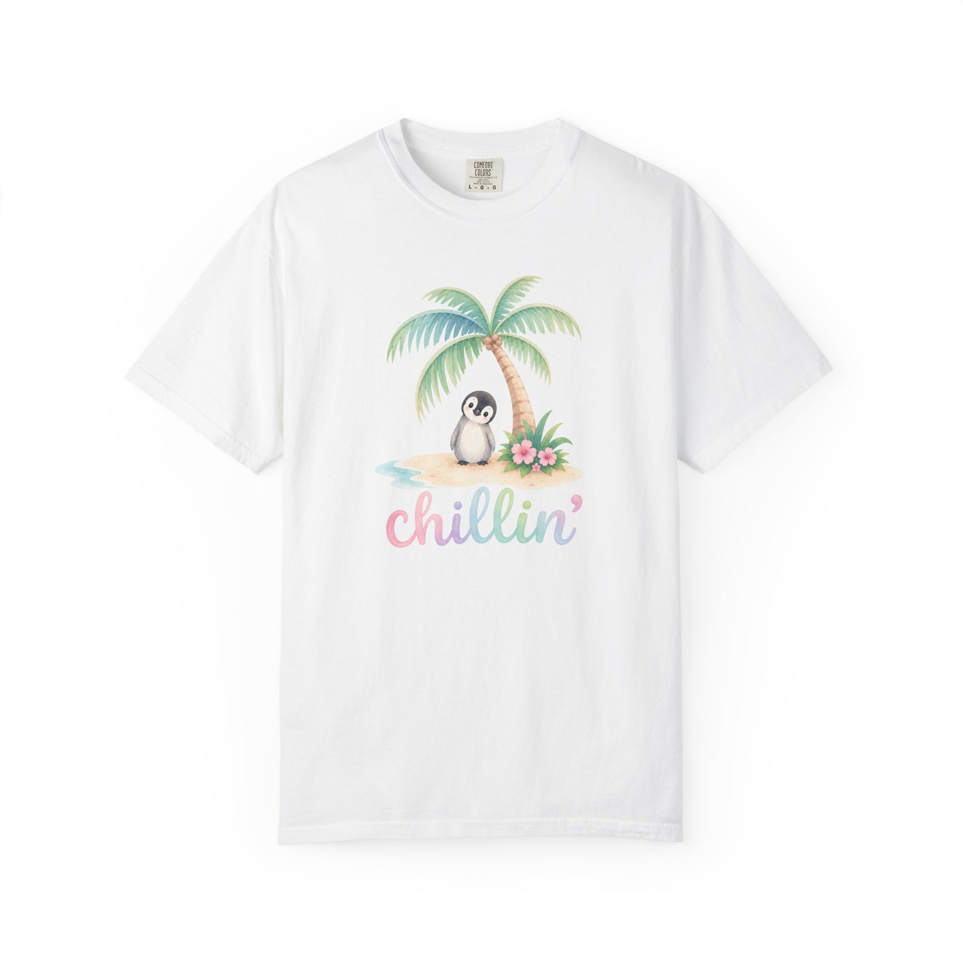 A white short-sleeve crewneck t-shirt featuring a colorful graphic of a penguin sitting under a palm tree on a beach with the word 'chillin'' written below in pastel pink and blue letters.