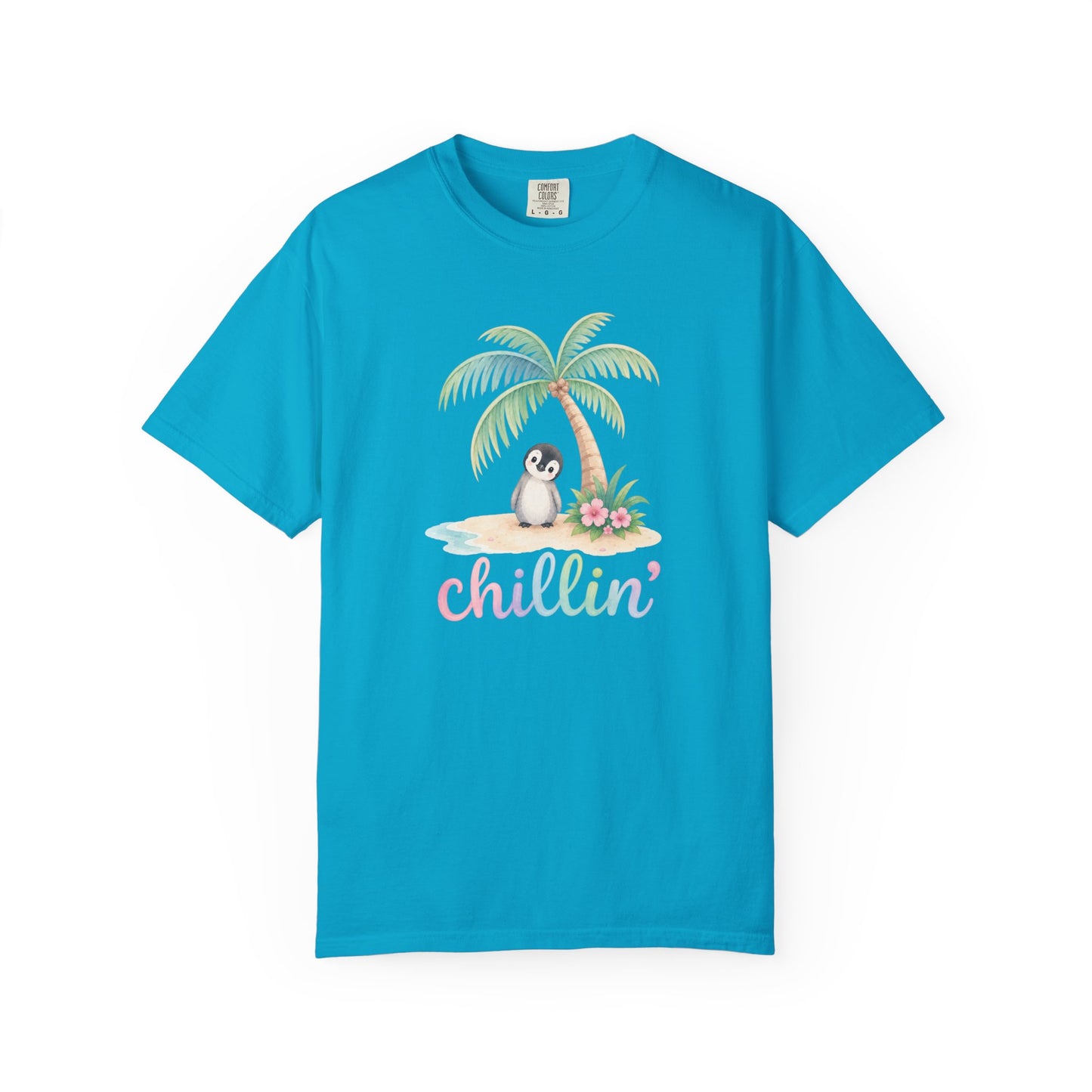 A bright turquoise blue short-sleeve t-shirt with a tropical graphic on the chest. The graphic features a small penguin sitting on a sandy beach under a palm tree with the word 'chillin'' written below in a pastel pink script.