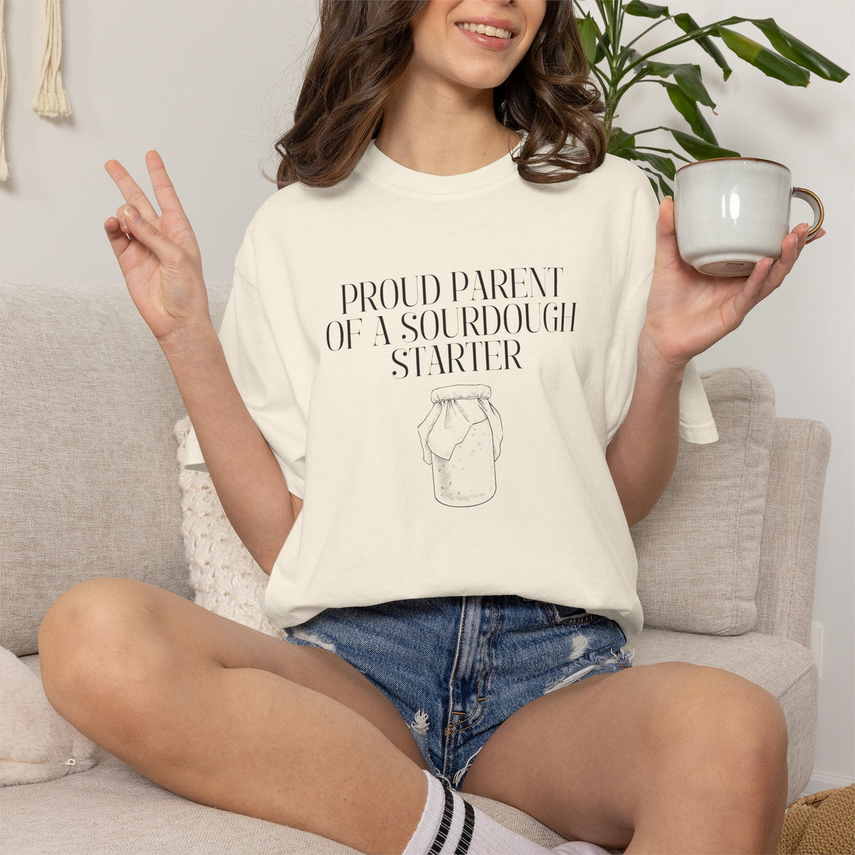 Model wearing an ivory Comfort Colors® "Proud Parent of a Sourdough Starter" t-shirt with vintage sourdough jar graphic. Funny sourdough shirt for bakers, bread makers, and homemade bread enthusiasts.