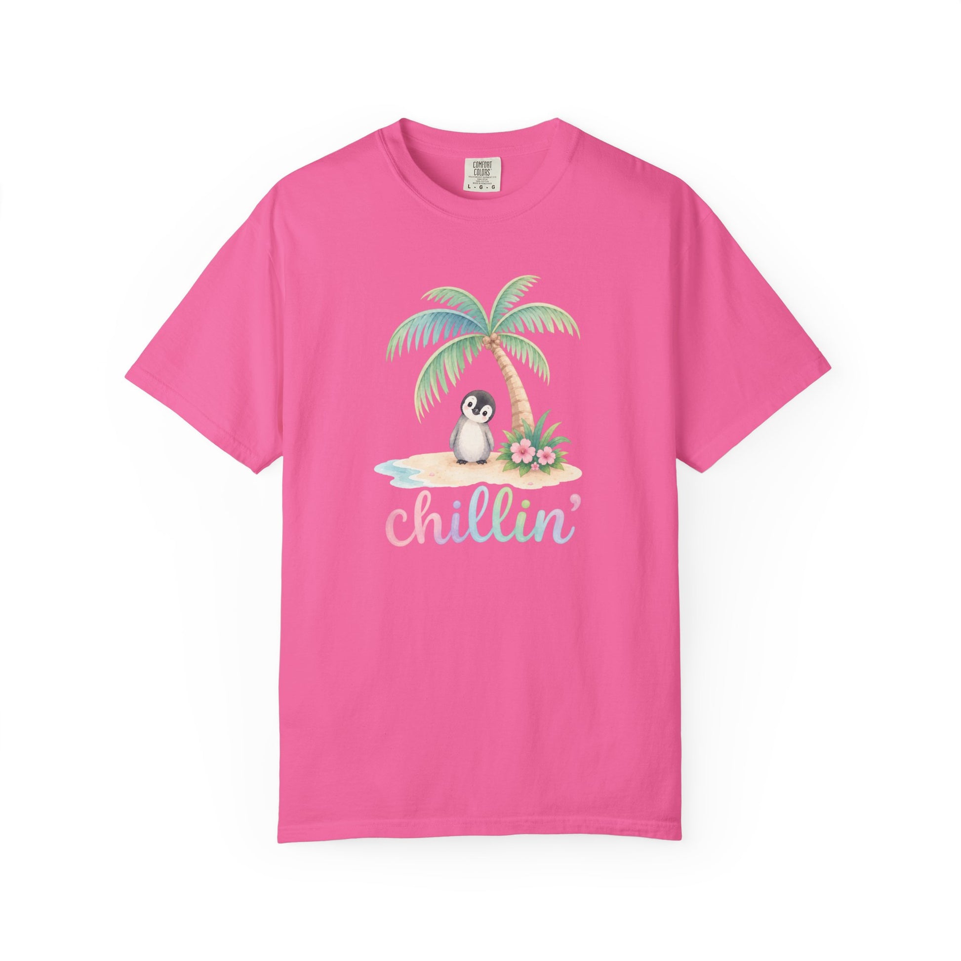 A bright pink short-sleeve crewneck t-shirt featuring a tropical graphic of a penguin sitting on a palm tree on a small beach with the word 'Chillin'' written below in pastel script.
