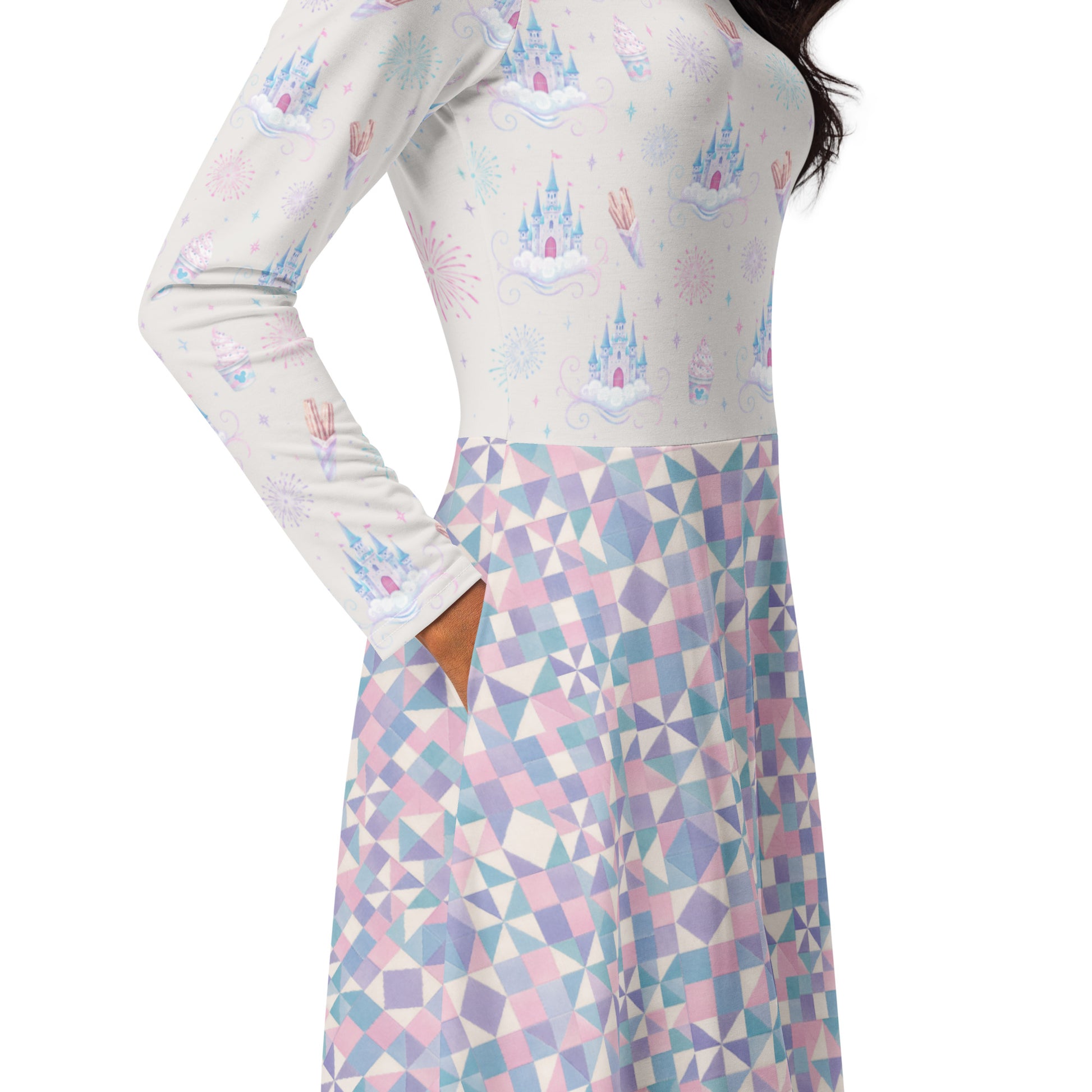 A woman wearing a long-sleeve dress with a pastel castle and fireworks print on the bodice and a pink, blue, and white geometric patterned skirt, shown against a plain white background.