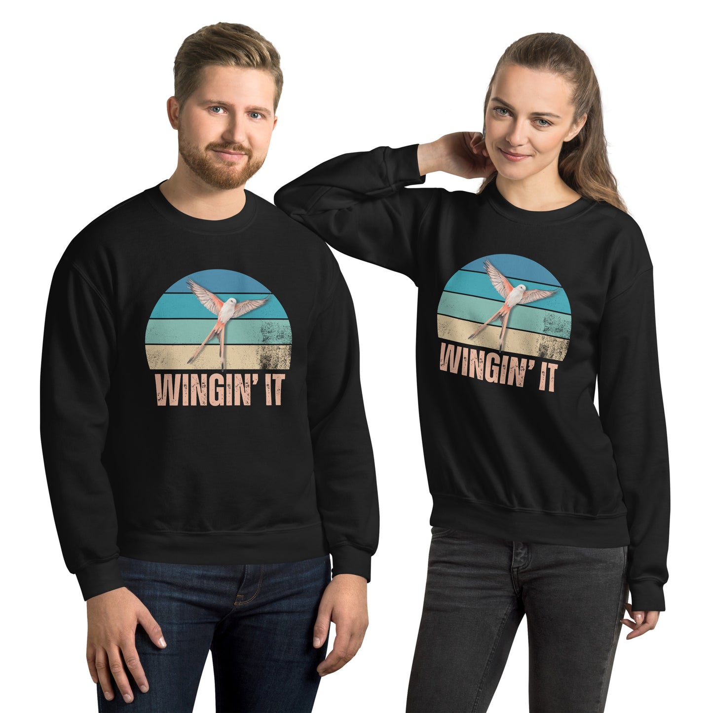 Smiling man and woman in black Wingin' It crewneck sweatshirts with a Wingspan-inspired scissor-tailed flycatcher and retro sunset design