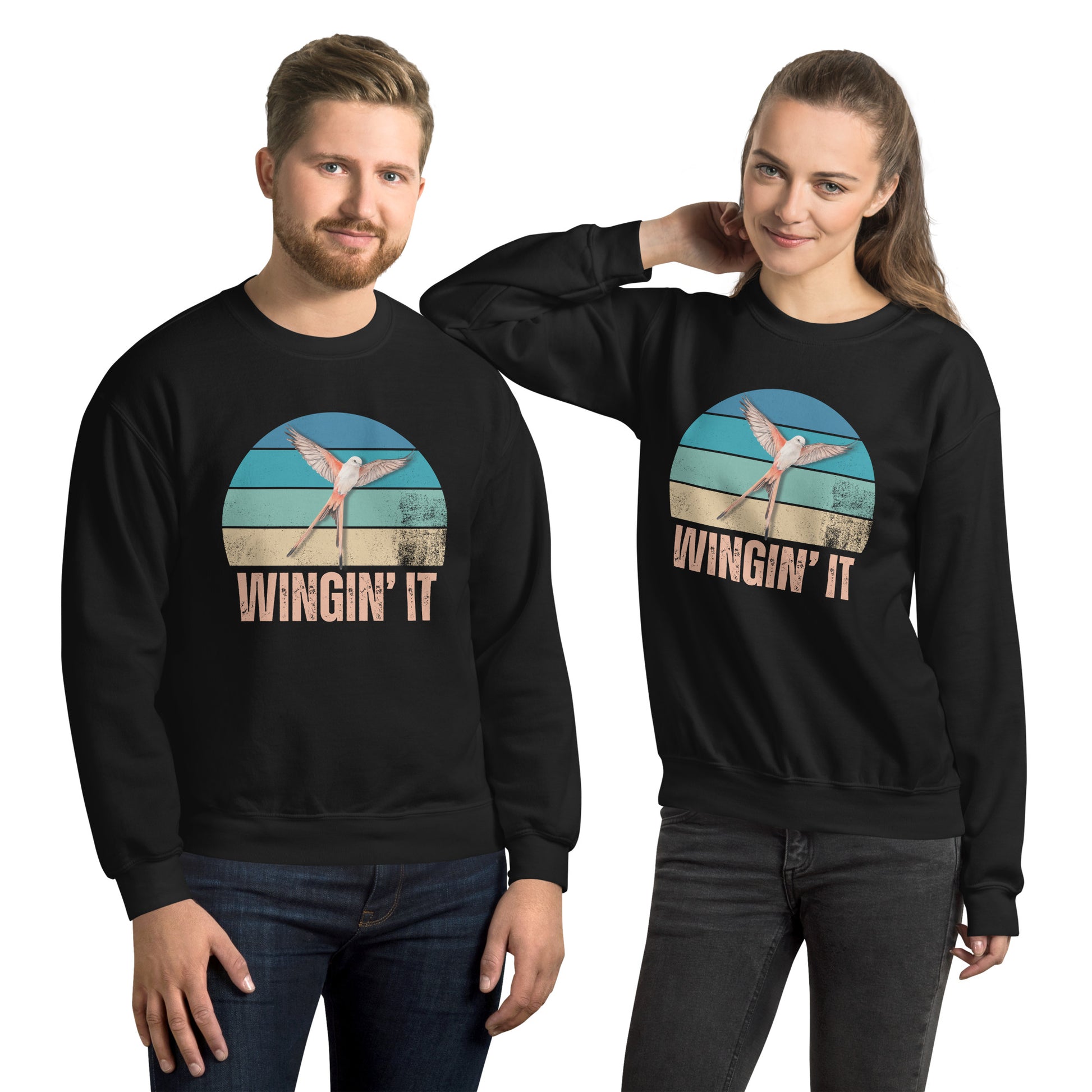 Smiling man and woman in black Wingin' It crewneck sweatshirts with a Wingspan-inspired scissor-tailed flycatcher and retro sunset design