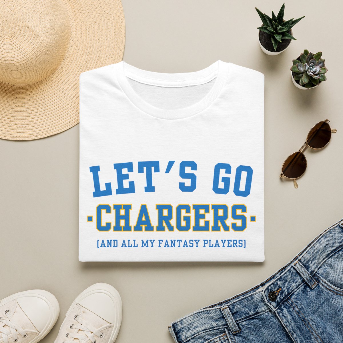 White Chargers fantasy football tee folded on a neutral flat lay with a straw hat and sneakers