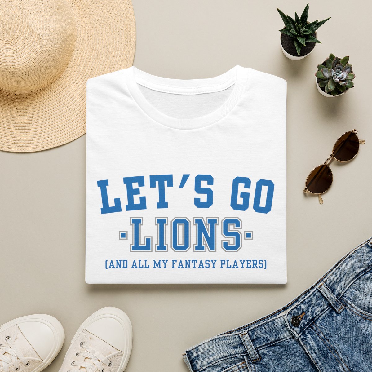 White Lions fantasy football tee folded on a neutral flat lay with a straw hat and sneakers