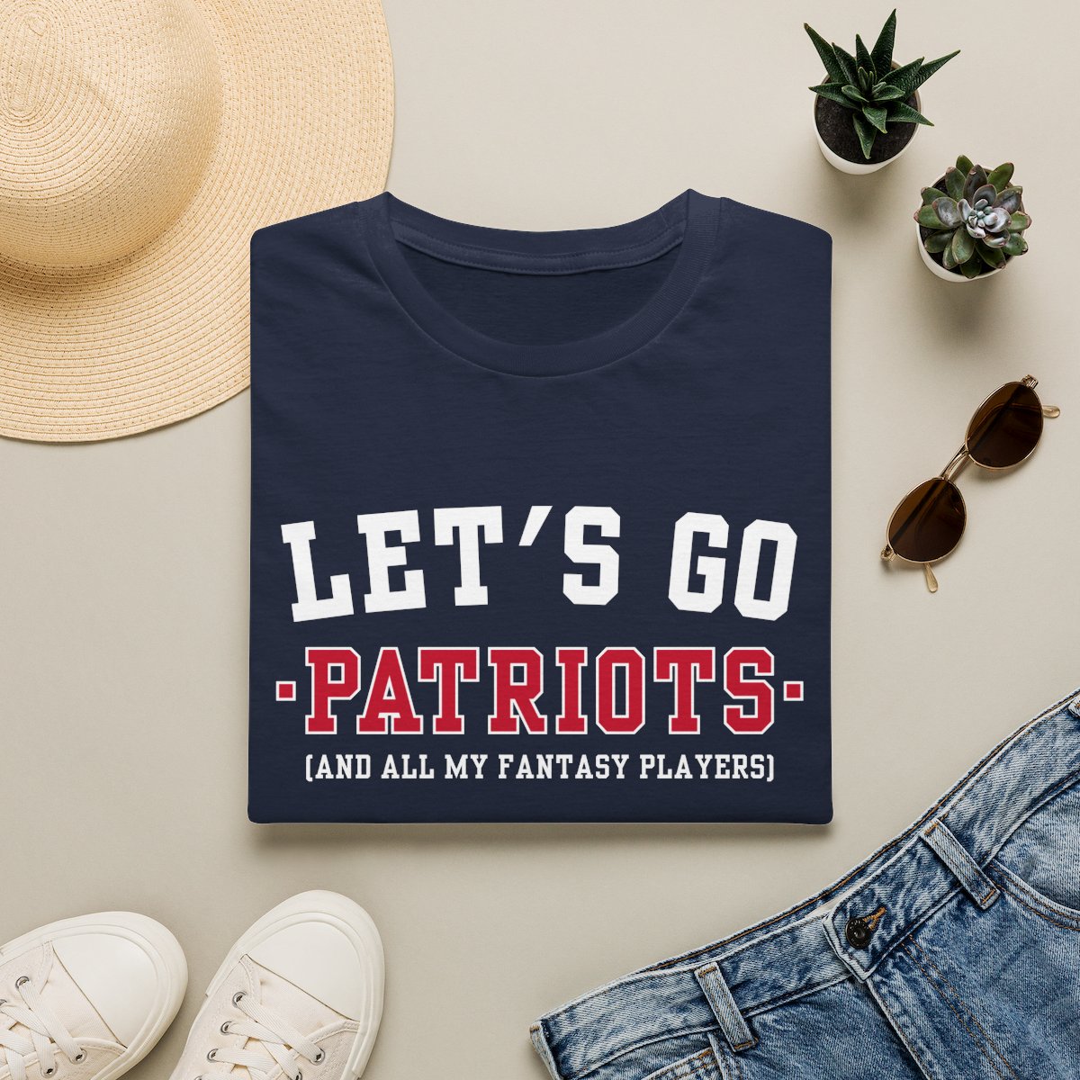 Navy Patriots fantasy football tee folded on a neutral flat lay with a straw hat and sneakers