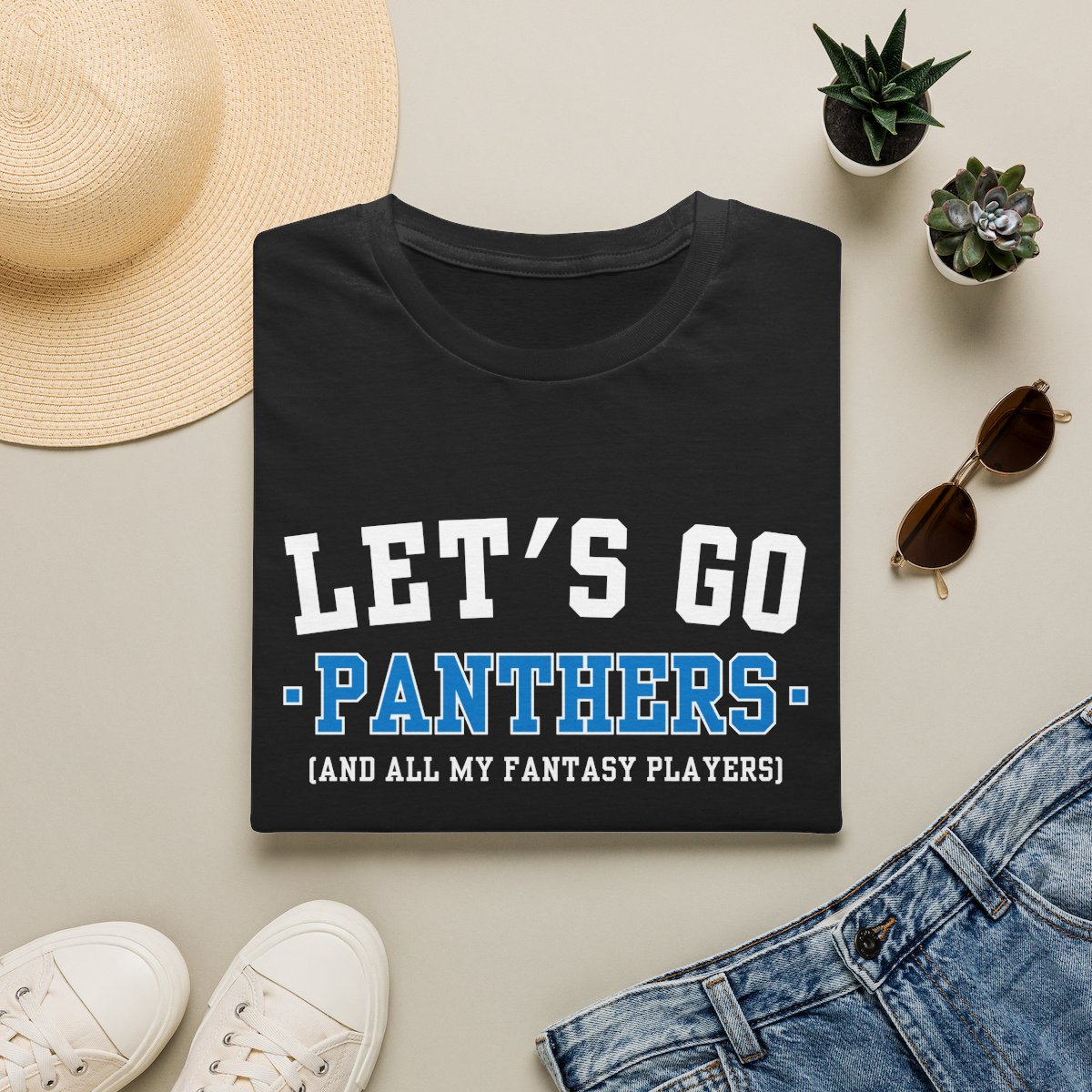 Black Panthers fantasy football tee folded on a neutral flat lay with a straw hat and sneakers