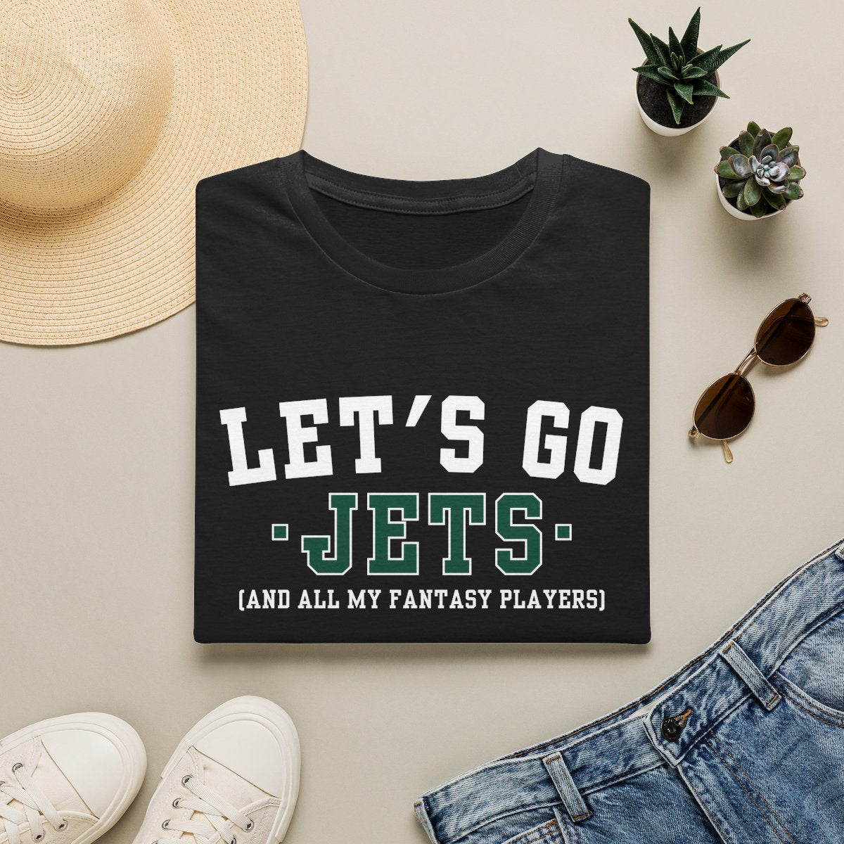 Black Jets fantasy football tee folded on a neutral flat lay with a straw hat and sneakers